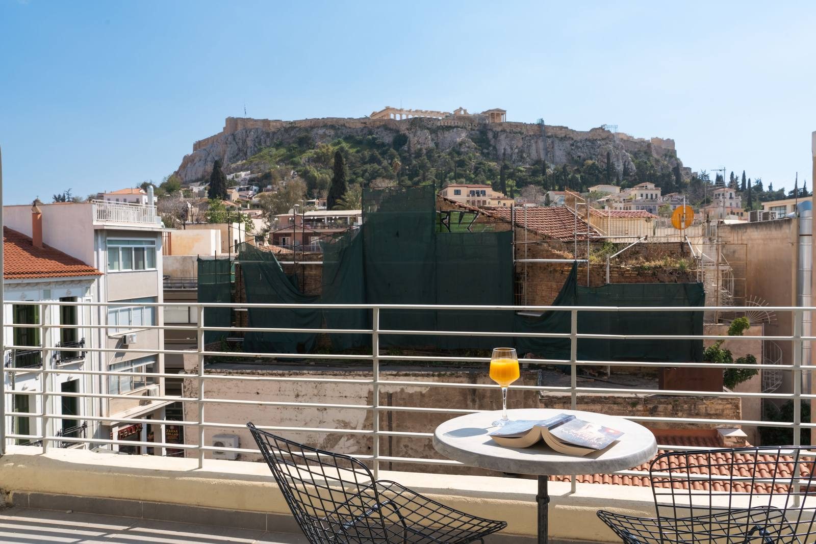 Terrace by day with a small table and the Acropolis behind the rooftops